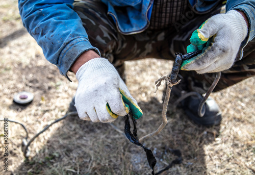 A worker repairs wiring at a construction site. Technology