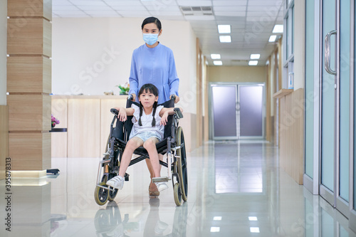 Small girl patient sit on wheelchair with nurse take care on lobby hospital