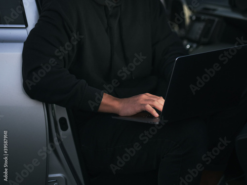 entrepreneur using laptop in car. low key photo without a face
