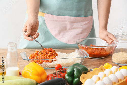 Woman cooking rice casserole on table, closeup