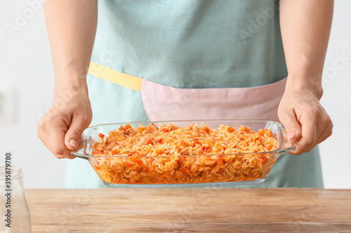 Obraz na plátně Woman cooking rice casserole on table, closeup