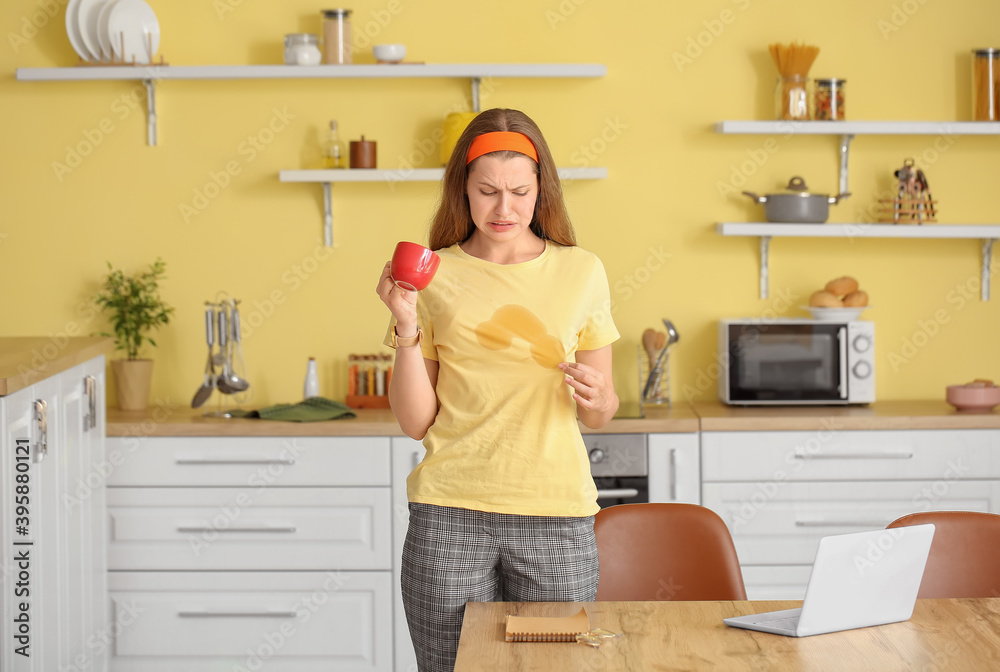 Stressed young woman with coffee stains on her t-shirt in kitchen Stressed young woman with coffee stains on her t-shirt in kitchen