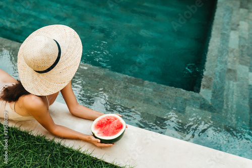 Young attractive woman in the pool enjoying delicious ripe watermelon. Bali Indonesia. Summer time, relaxation, travel content.