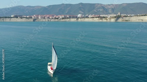 Circling aerial shot of sailboat cruising the sea.