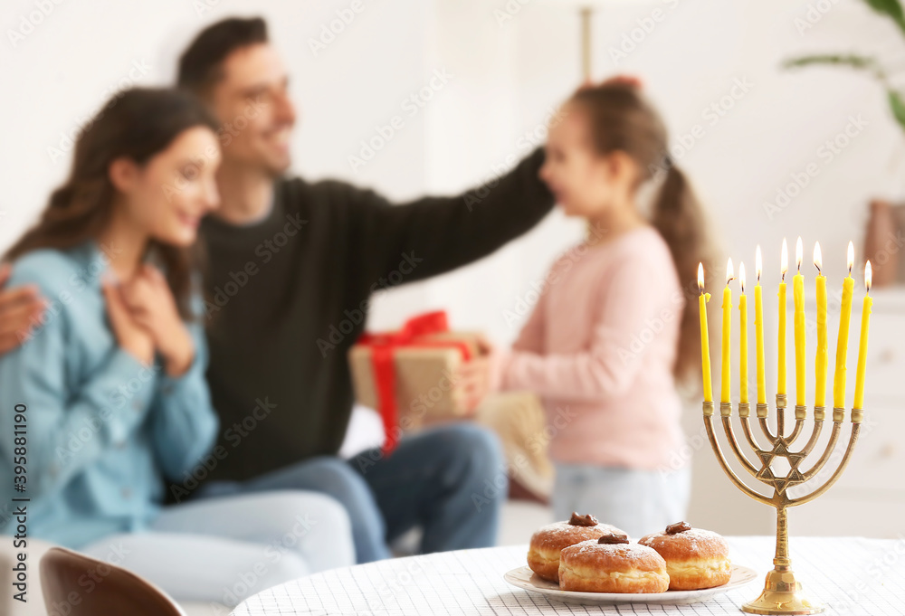 Menorah and donuts on table of happy family celebrating Hannukah at home Menorah and donuts on table of happy family celebrating Hannukah at home