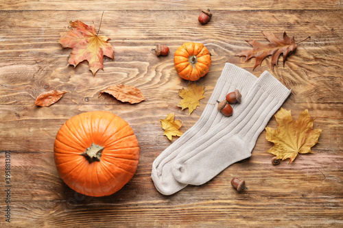 Warm socks, autumn leaves and pumpkins on wooden background