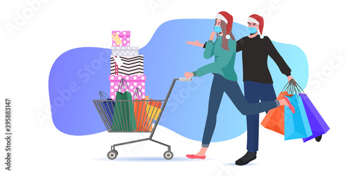 couple in santa hats and masks pushing trolley cart with shopping bags and gifts new year big sale coronavirus quarantine concept full length horizontal vector illustration © mast3r