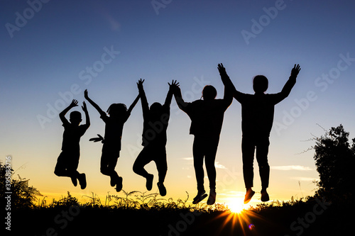 Silhouette of happy children jumping playing on mountain at sunset time