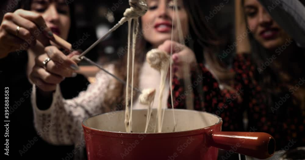 Cheese fondue with three beautiful women. We can see the bread soak in the melted cheese. Perfect meal with friends 4K