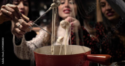 Cheese fondue with three beautiful women. We can see the bread soak in the melted cheese. Perfect meal with friends 4K