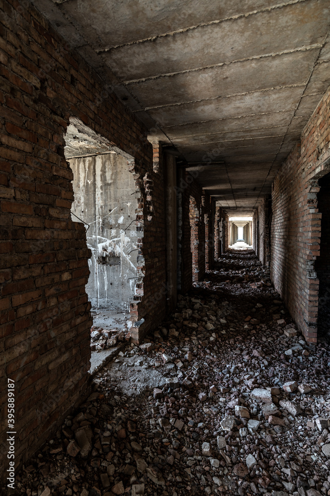 A long dark corridor in a dilapidated modern concrete building with broken brick walls