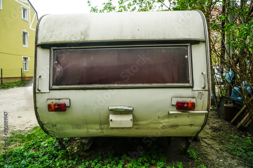 old rusty travel trailer (camper trailer, camper van, caravan). Side view.Caravan Trailer Near house. Summer Holidays Road Trip Travel Concept.emblem of berlin