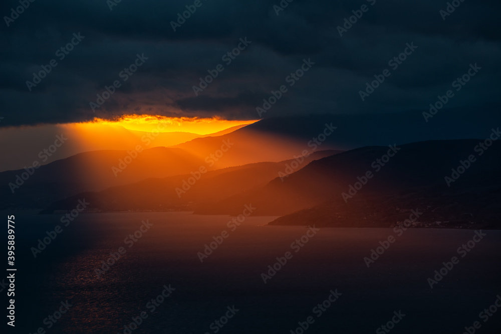 The last rays through the dark clouds at sunset illuminate the southern coast of Crimea
