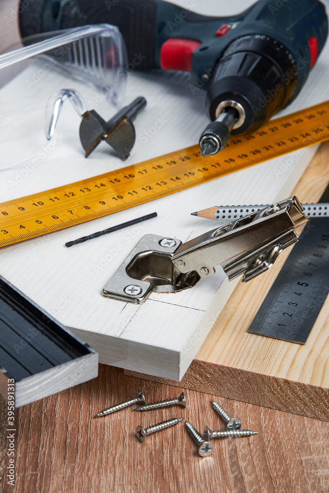Installation of furniture hinges in the chipboard, tools and accessories needed to perform the work. Small carpentry work at home, the concept of a home master, self-repair of the house Installation of furniture hinges in the chipboard, tools and accessories needed to perform the work. Small carpentry work at home, the concept of a home master, self-repair of the house