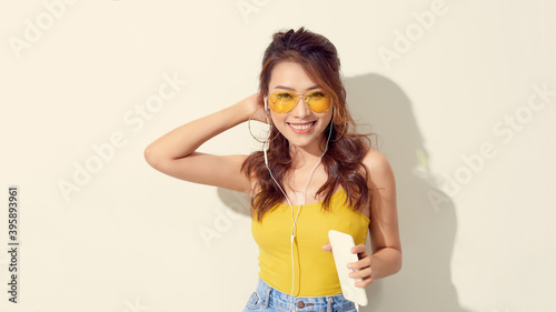 Happy carefree young woman dancing and listening to music from smartphone over white background