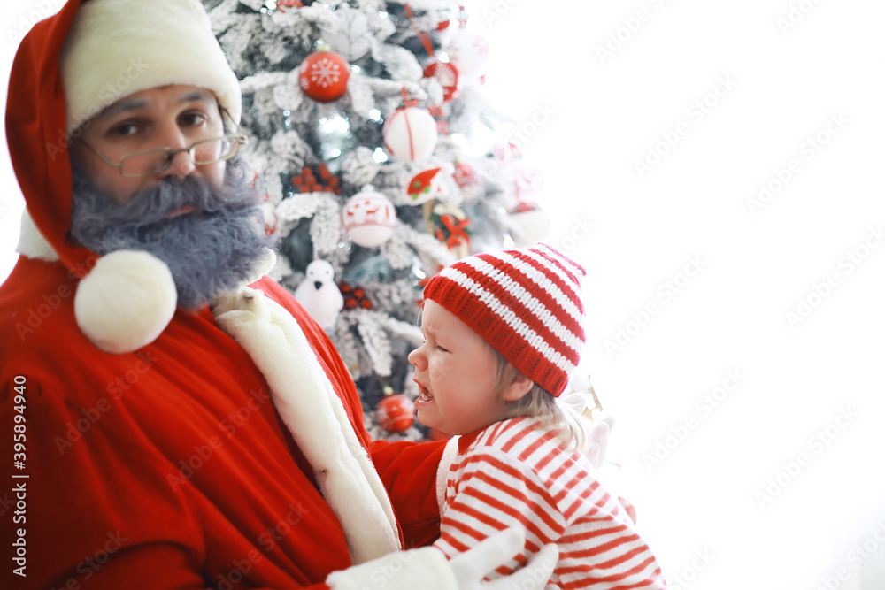 Obraz premium Santa Claus sitting with little cute elves over Christmas background. Time of miracles. Gifts from Santa Claus.