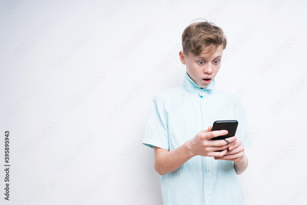A Caucasian boy is looking surprised by something on the phone A Caucasian boy is looking surprised by something on the phone