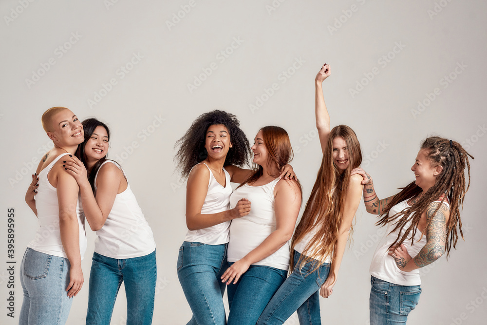 Group of six beautiful diverse young women wearing white shirt and ...