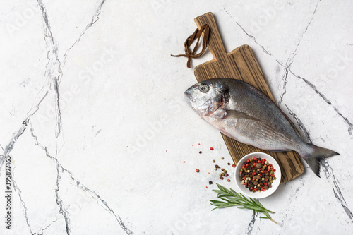 Fresh fish dorada or gilt-head bream on cutting board with spices