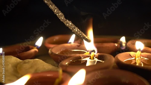 slow motion side shot of Phuljhadi being lit from a diya oil lamp placed in a plate with it lighting up and sparks flying out shot on the indian festival of Diwali photo