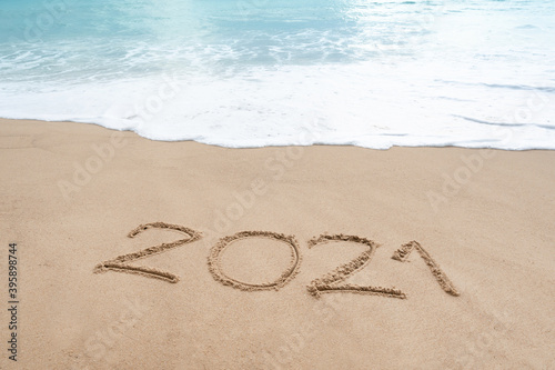 Hello 2021 sign on the sandy beach with soft wave of white foam. Welcoming 2021 with new resolutions  dreams concept.