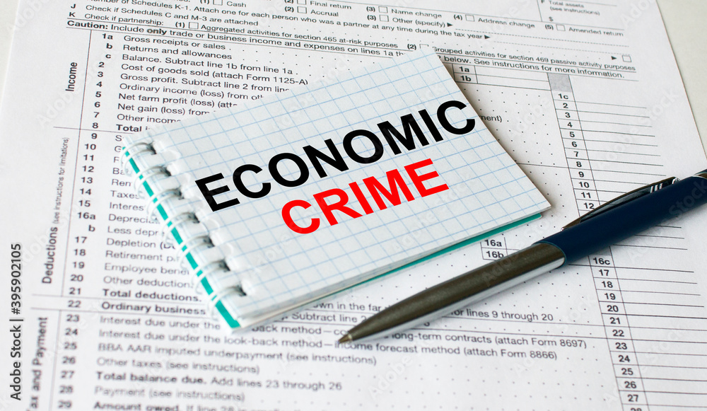 Notepad with text Economic Crime lying on financial tables with a pen Notepad with text Economic Crime lying on financial tables with a pen
