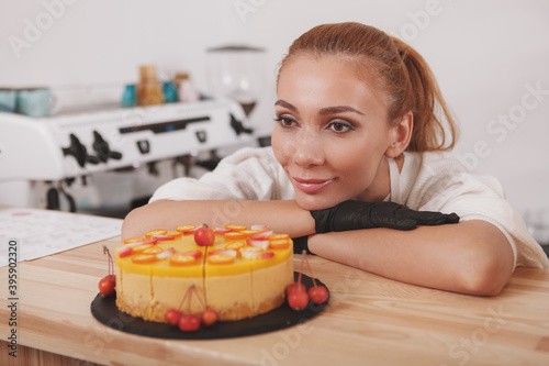 Gorgeous young woman looking at freshly made raw vegan cake she is selling at her coffee shop