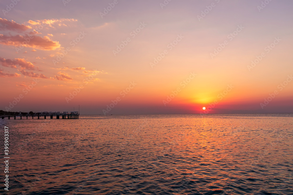 amazing picturesque view at a pier in sea with calm water and beautiful sunset on a background. Scenic costal view on shoreline with hotel in tourist season amazing picturesque view at a pier in sea with calm water and beautiful sunset on a background. Scenic costal view on shoreline with hotel in tourist season