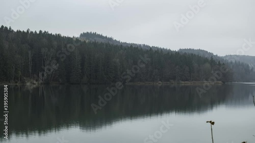 Bewegter Zeitraffer über einen Stausee mit bewaldetem Ufer im Herbst bei Nebelwetter photo