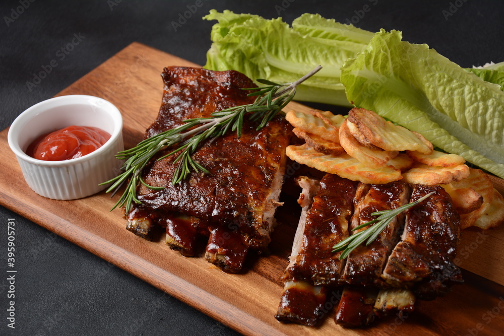 Closeup of pork ribs grilled with BBQ sauce and caramelized in honey. Tasty snack to beer on a wooden Board. Grilled pork ribs with spices on a stone background