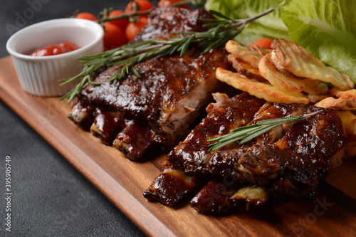 Closeup of pork ribs grilled with BBQ sauce and caramelized in honey. Tasty snack to beer on a wooden Board. Grilled pork ribs with spices on a stone background