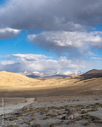 Spectacular view on snow-capped mountains from high-altitude Khargush pass in Gorno-Badakshan, the Pamir region of Tajikistan with dirt road