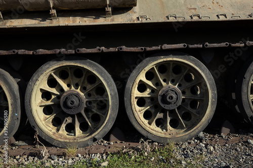 Detail of old aged military vehicle with continous track and wheels. Tank is corroded, rusty, tarnished and faded.