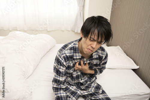 昨日の飲み会が遅くまで続き、朝胸焼けが酷く起きれないパジャマ姿の男性 photo