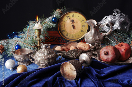 Burning candle, clock face, fir branch and Christmas decorations.