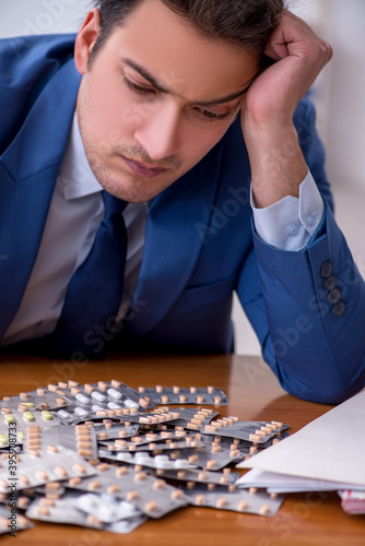 Young male sick employee suffering at workplace