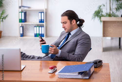 Fotografía Young male employee drinking coffee in the office