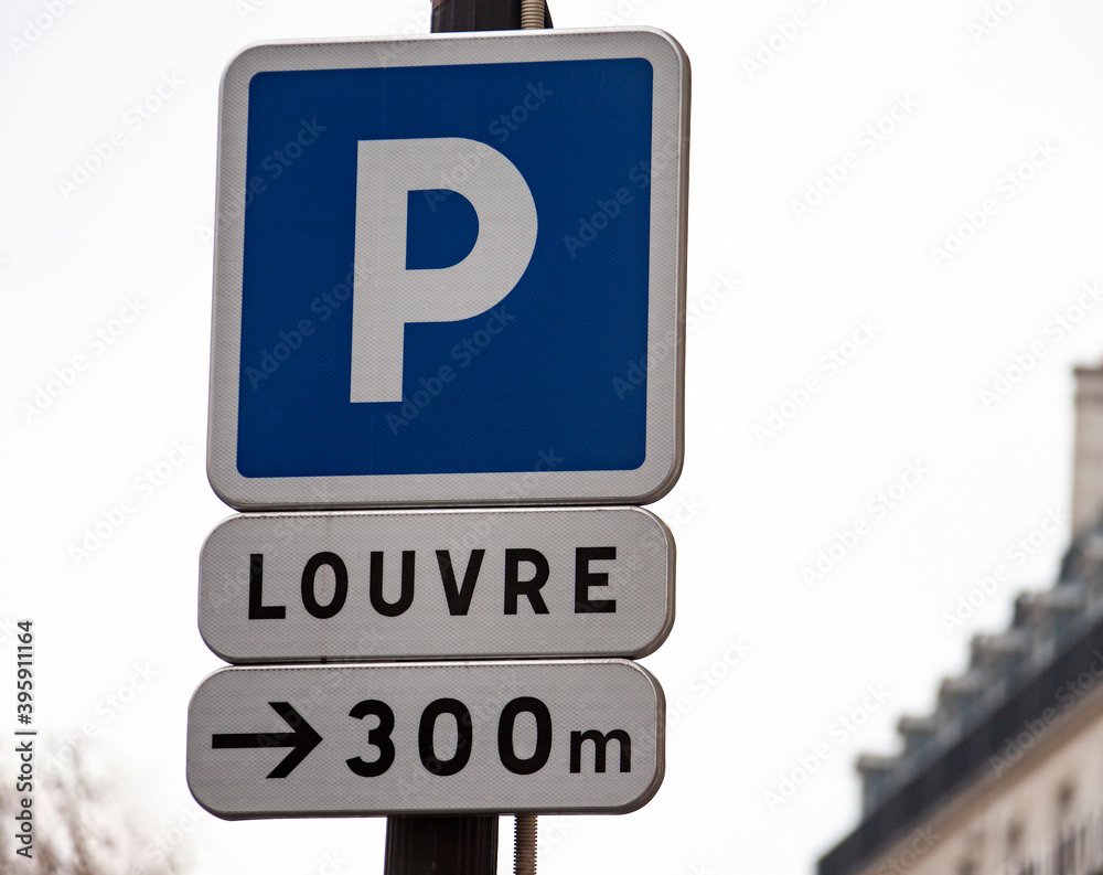 Parking road sign and signpost from the distance to the Louvre in Paris. Parking road sign and signpost from the distance to the Louvre in Paris.