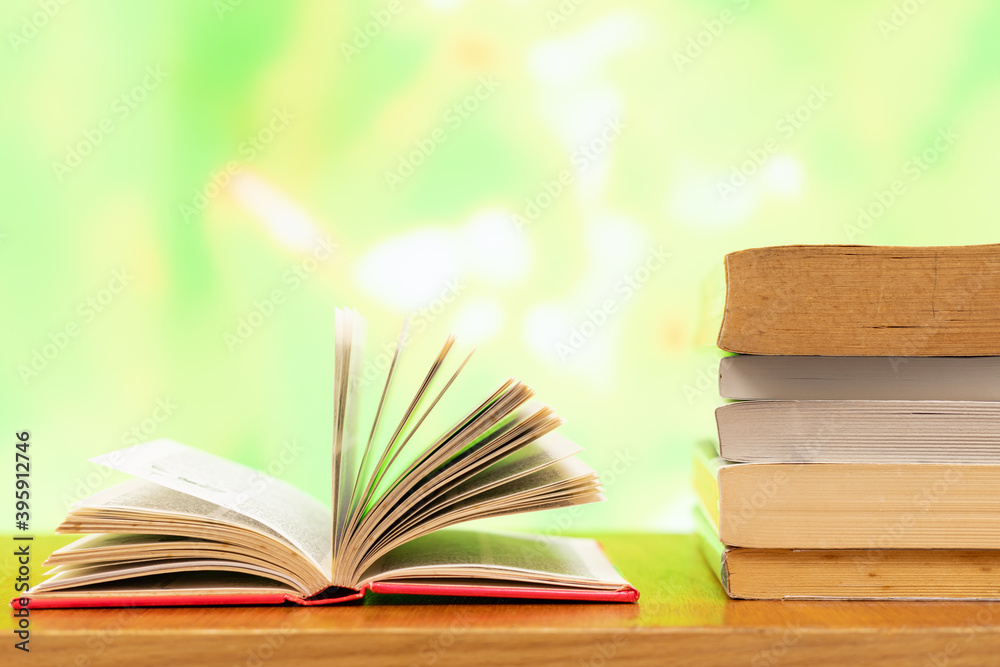 A pile of books and open book with blurred colour as background and copy space A pile of books and open book with blurred colour as background and copy space