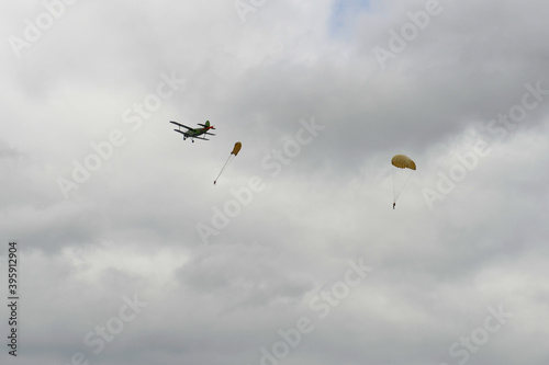Skydivers jump from an old biplane plane on a cloudy day
