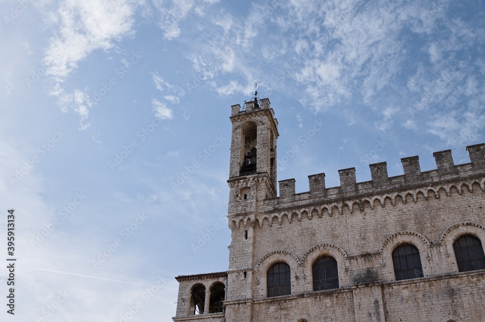 An ancient bell tower of a medieval building with battlements and architectural decorations (Gubbio, Umbria, Italy)
