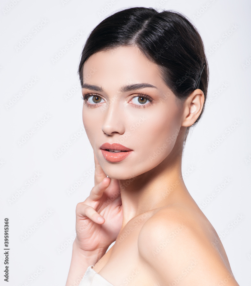 Fototapeta premium Portrait of beautiful brunette girl which touching her fresh face. Beautiful face of young woman with health fresh skin. Beautiful face of young adult woman with clean fresh skin. Skin care.