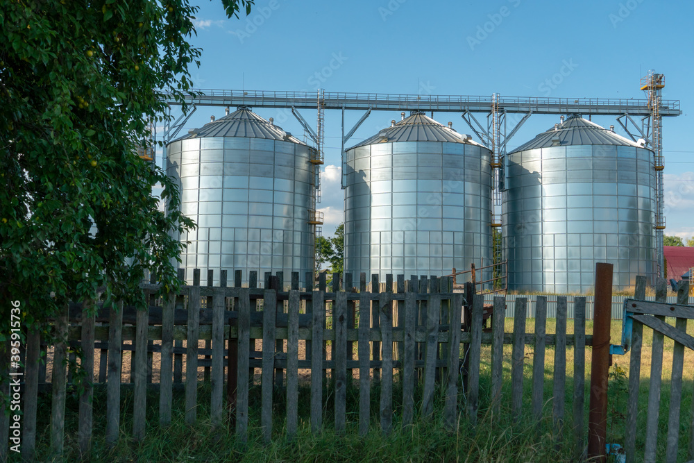 Fototapeta premium silver silos on agro manufacturing plant for processing drying cleaning and storage of agricultural products, flour, cereals and grain. Large iron barrels of grain. Granary elevator