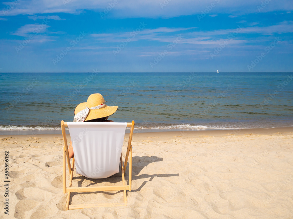 Woman relaxing on beach sitting on sunbed
Woman relaxing on beach sitting on sunbed
