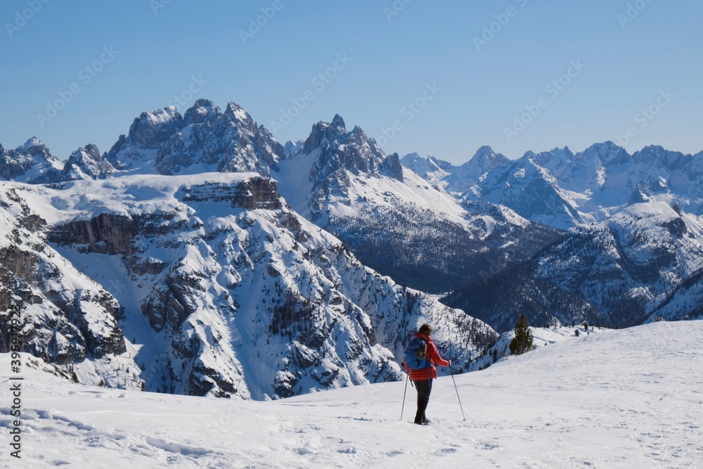 Mountain view with silhouette of walking tourist in red jacket in beautiful winter sunny scenery. Strudelkopf, Platzwiese (Piazza Prato), Dolomites, Italy