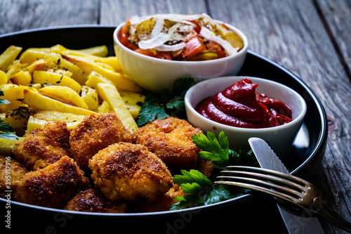 Fried breadcrumb chicken nuggets with French fries and vegetables 