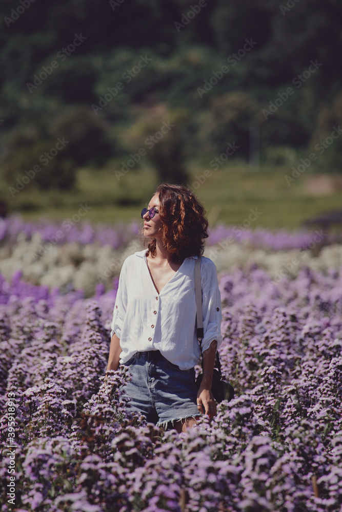 young woman professional photographer on a flower field in summer