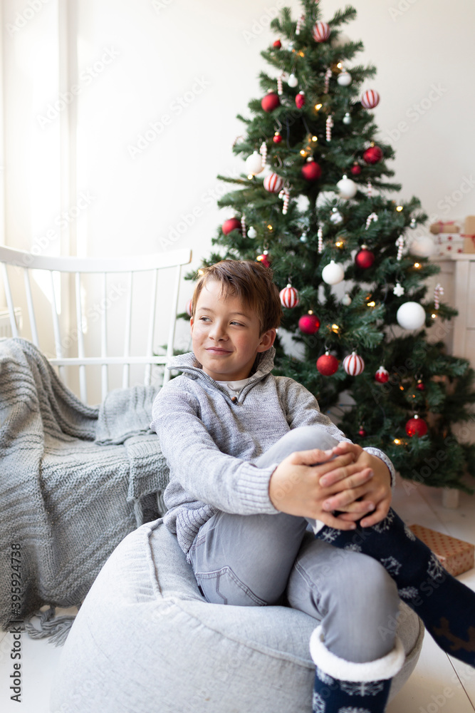 Christmas time - Young boy in front of a Christmas tree wondering if sant really exists