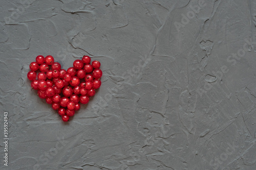 Red heart of currants on a gray concrete background. Heart shaped berries. Valentine's Day.