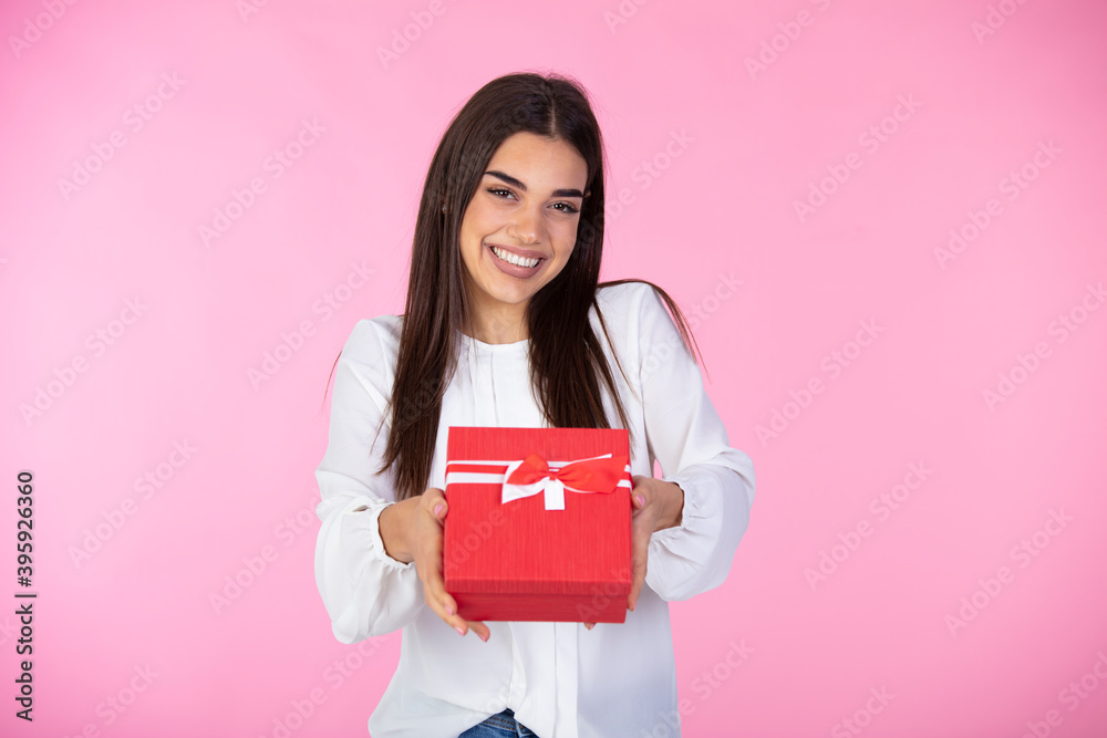 Young woman portrait hold gift. Smiling happy girl on pink background. Cheerful beautiful woman and charm gift decoration joy party. Attractive young woman holding gift boxes over pink background Young woman portrait hold gift. Smiling happy girl on pink background. Cheerful beautiful woman and charm gift decoration joy party. Attractive young woman holding gift boxes over pink background